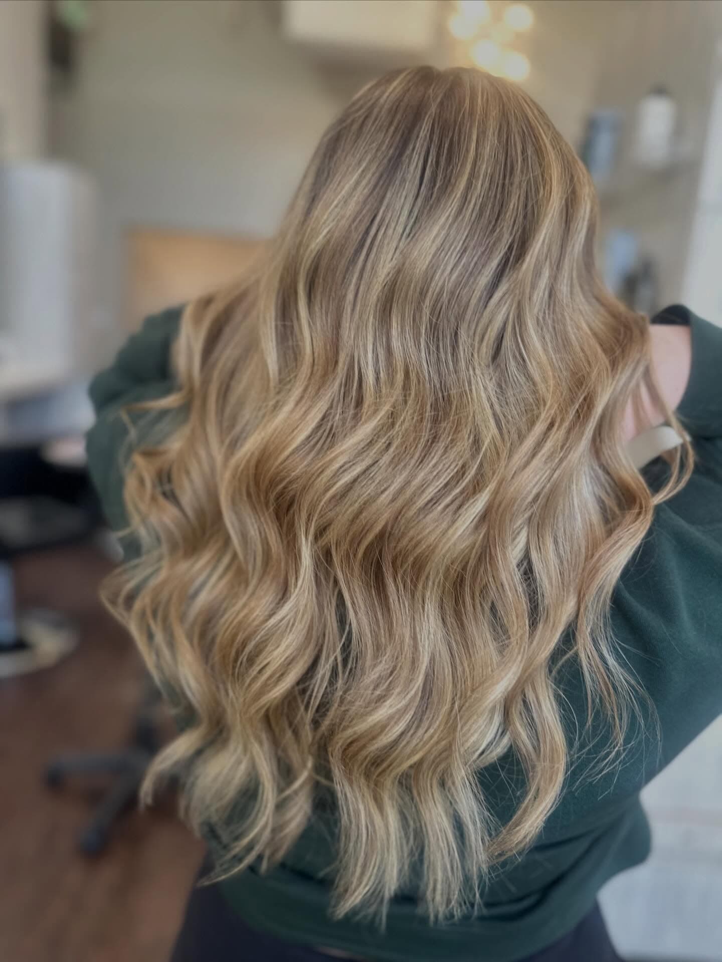 Long, dimensional golden-blonde balayage with soft waves, styled at Lee Graves Salon near Wylie, TX