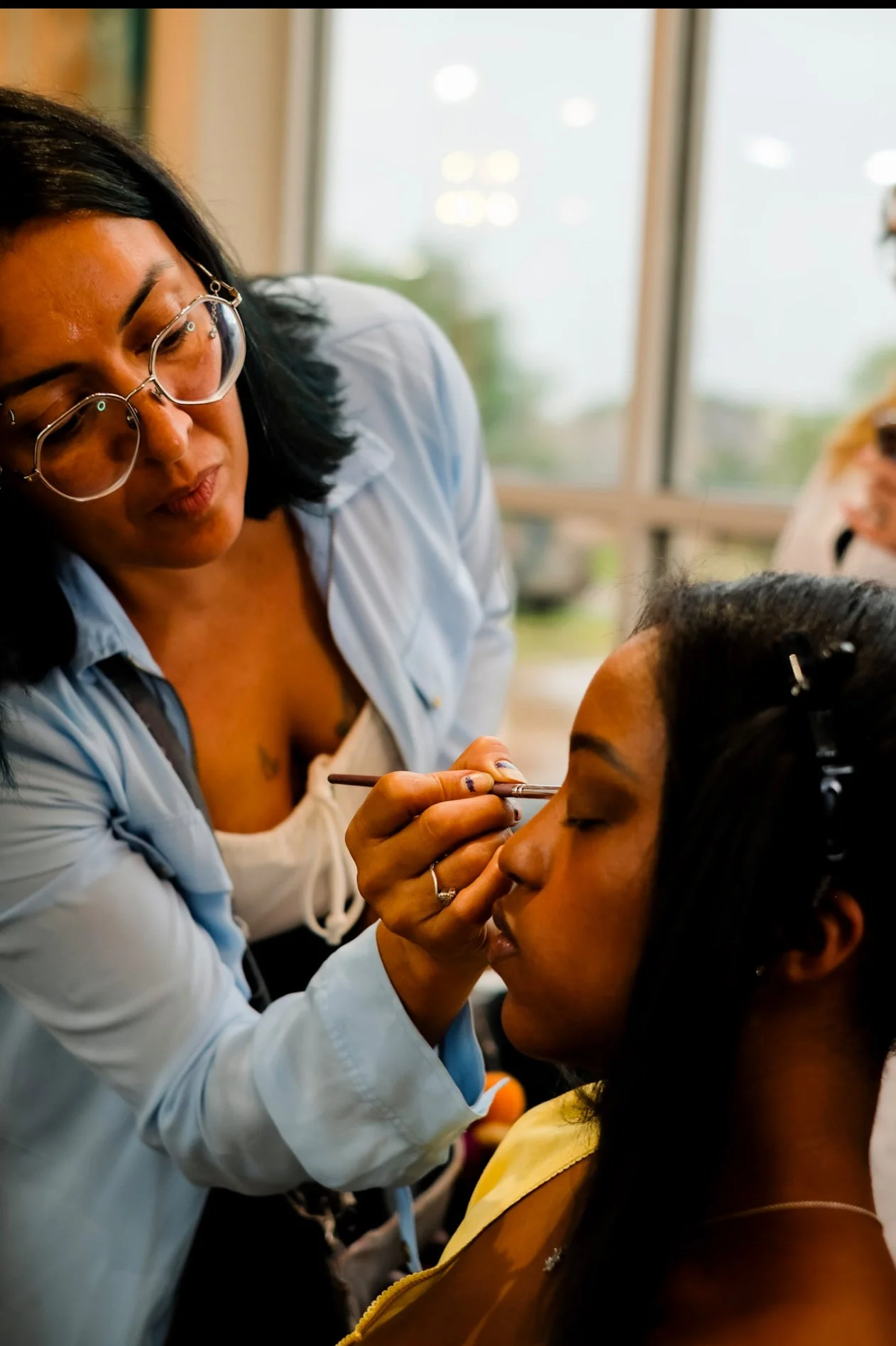A Something Blue makeup artist working on a client's eye makeup in a getting-ready room