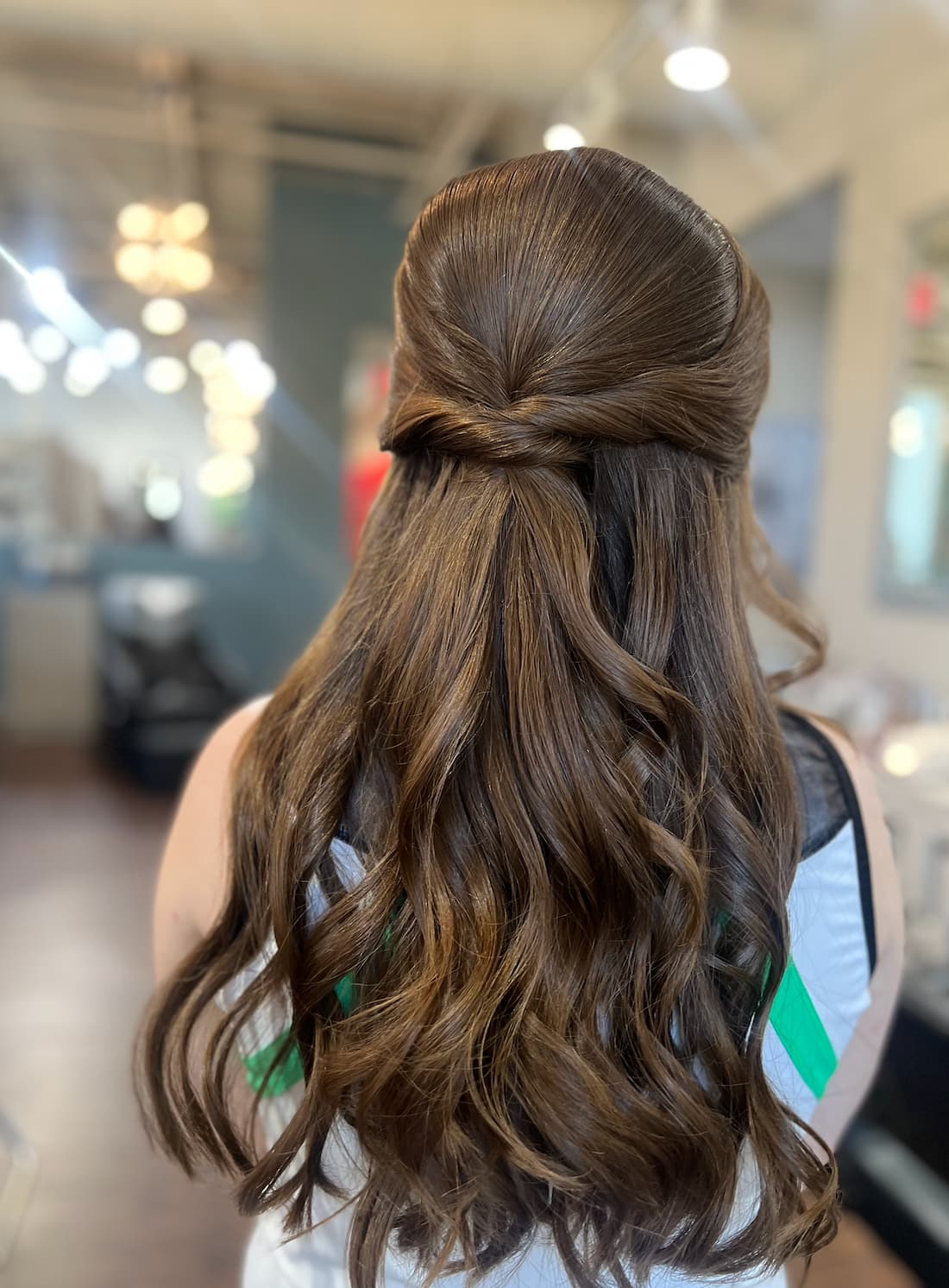 A half-up bridal party style with soft waves and a twisted crown section, styled at Lee Graves Salon in Plano, TX