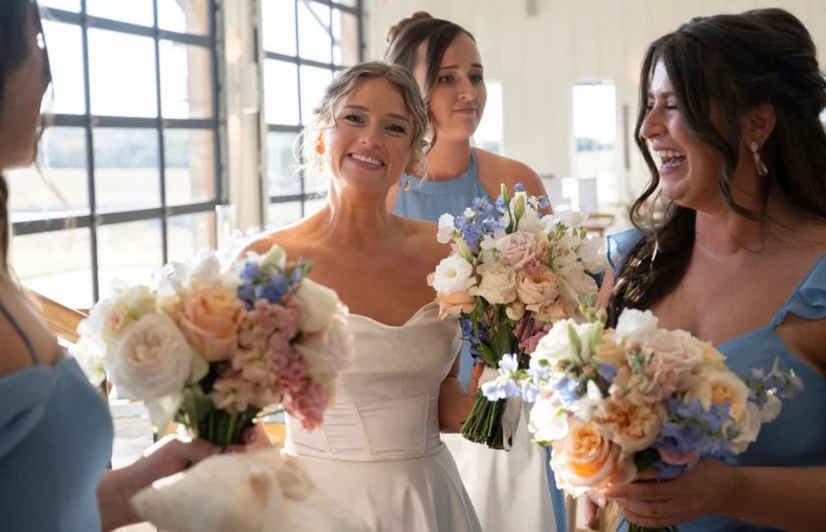 A bride and two bridesmaids holding bouquets, hair finished and styled by Something Blue by Lee Graves